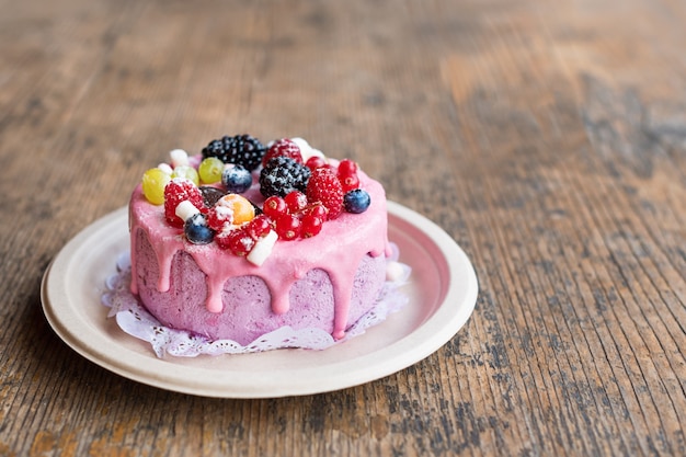 Torta di formaggio dolce con frutti di bosco freschi e crema allo yogurt. Delizioso dolce lampone con fragole fresche, lamponi, mirtilli, ribes e frutti di mora su superficie di legno con spazio di copia.