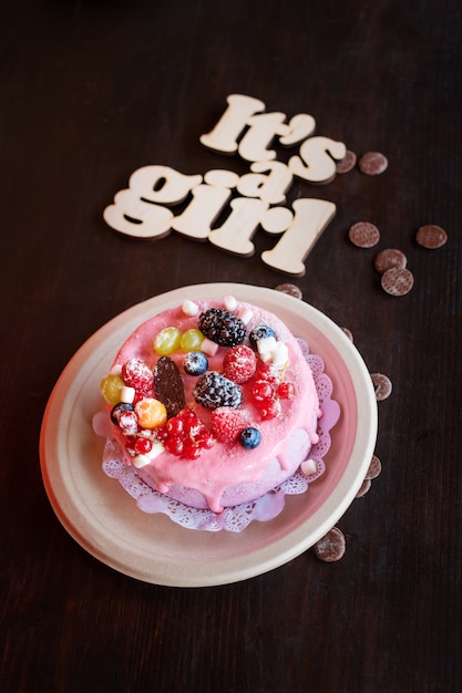 Torta di formaggio dolce con frutti di bosco freschi e crema allo yogurt e cartello in legno It's A Girl. Dolci per feste baby shower.