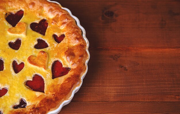 Torta di fragole per San Valentino con cuori su fondo in legno