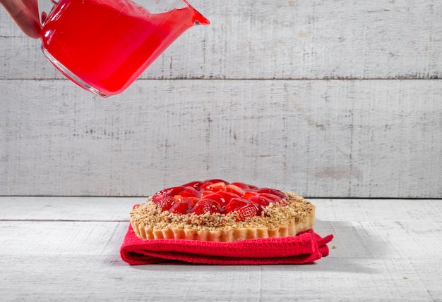 Torta di fragole su legno rustico bianco con ciotola di sciroppo di colata.