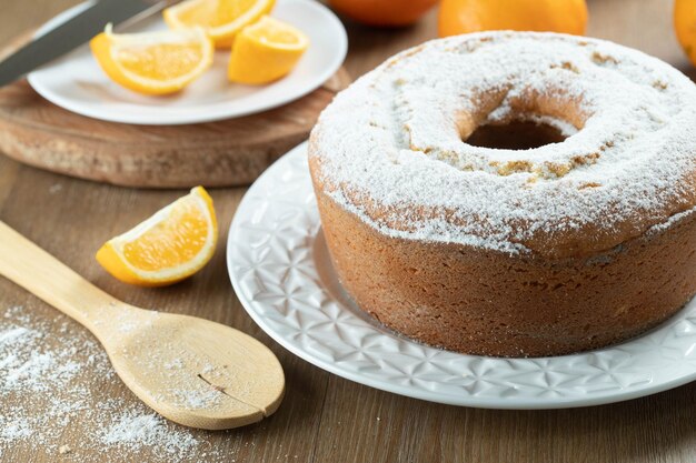 Torta di frutta arancione umida sul piatto con fette d'arancia sul tavolo di legno Deliziosa colazione tradizionale inglese tea time Ricetta della torta arancione