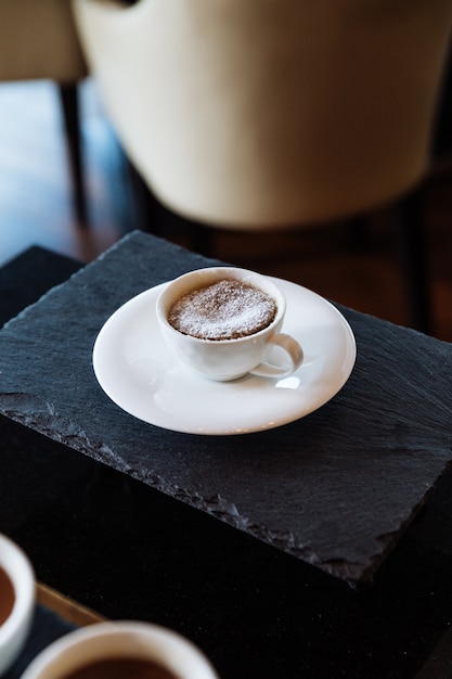 Torta di lava al cioccolato farcita con zucchero a velo all&#39;interno di tazza in ceramica bianca.