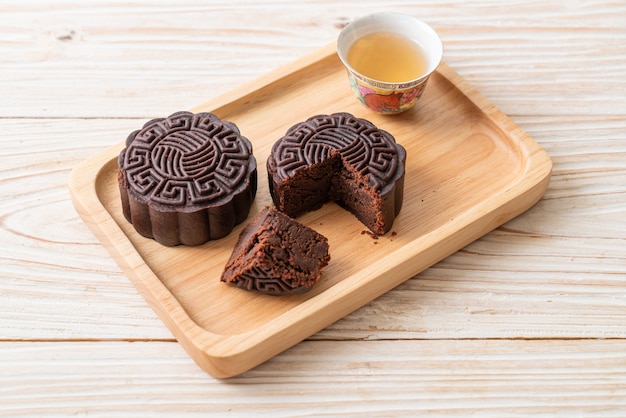 Torta di luna cinese sapore di cioccolato fondente sul piatto di legno