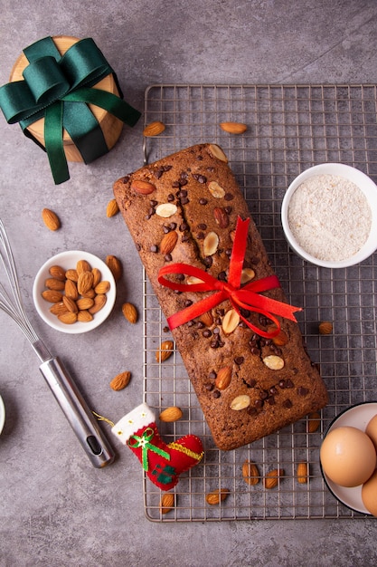 Torta di mandorle con scaglie di cioccolato con decorazioni natalizie su sfondo grigio