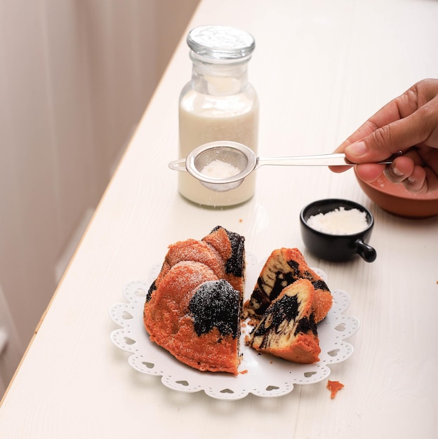 Torta di marmo con caffè con zucchero in polvere e utensili da cucina vintage, concetto di panetteria bianca