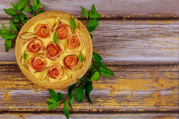 Torta di mele a forma di rosa su fondo di legno rustico vista dall'alto