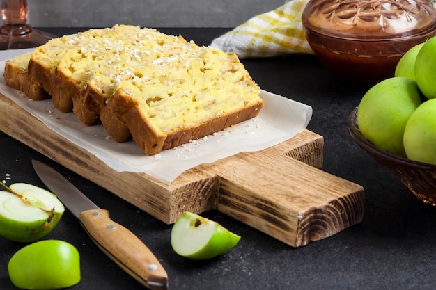 Torta di mele affettate e cocco su tagliere di legno su sfondo scuro