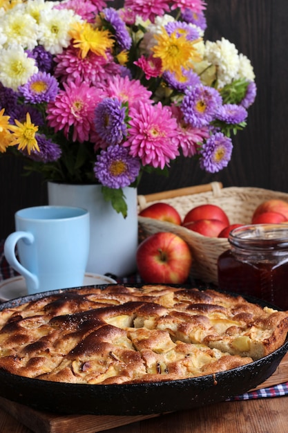 Torta di mele al forno a casa. Il cibo è ancora in stile rustico. Dessert e un bouquet di fiori coltivati.