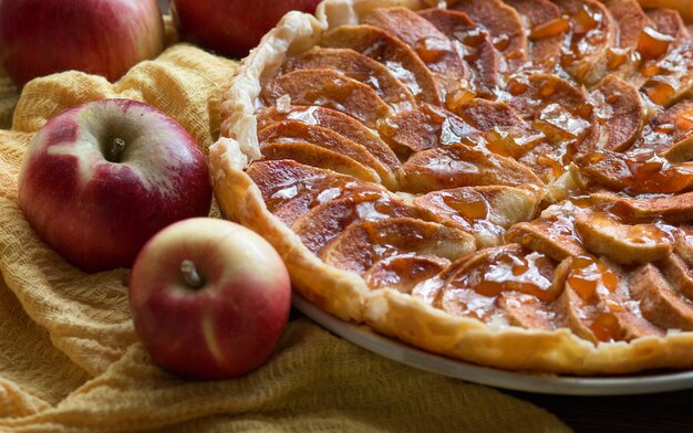 Torta di mele con mela fresca alla cannella e salsa di caramello su un piatto su un tavolo di legno scuro