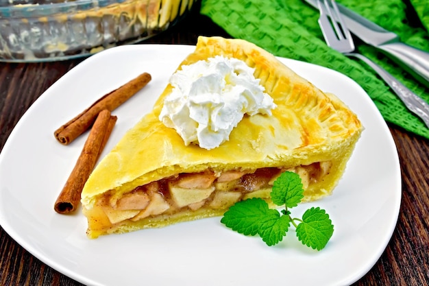 Torta di mele con panna e menta nel piatto a bordo