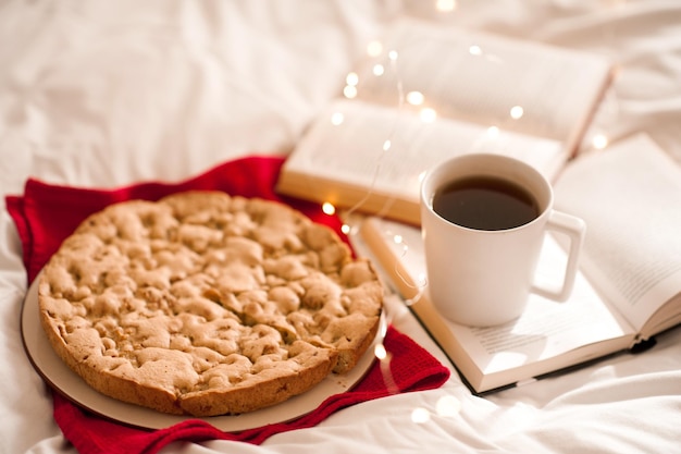 Torta di mele con una tazza di caffè sui libri aperti a letto. Buon giorno. Colazione.