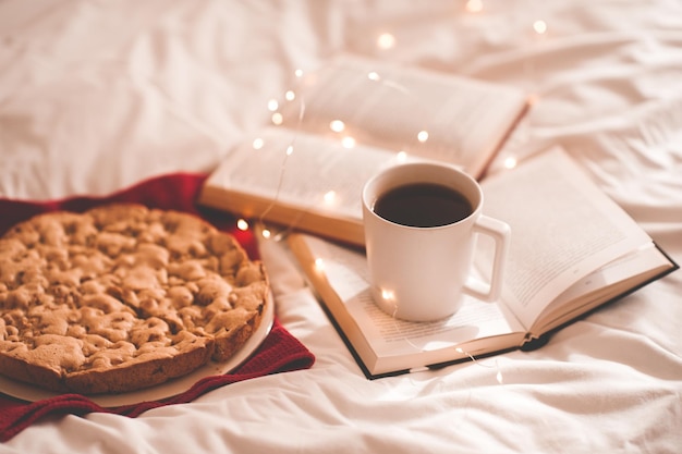 Torta di mele con una tazza di caffè sui libri aperti a letto Buongiorno colazione