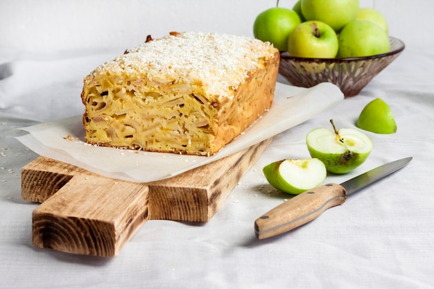 Torta di mele e cocco su tagliere di legno e mele in vaso