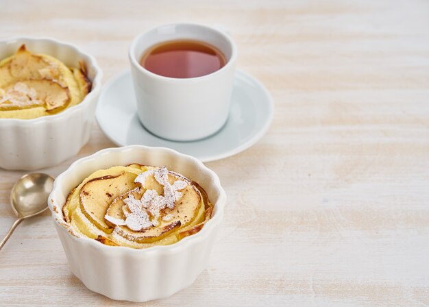 Torta di mele e tazza di tè sulla tavola di legno bianca in cucina