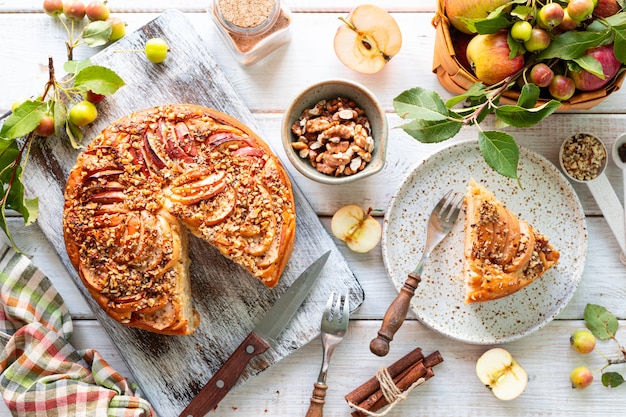 Torta di mele fatta in casa e ingredienti su una superficie di legno bianca