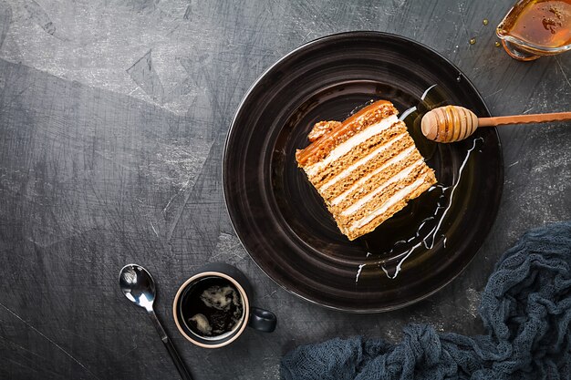 Torta di miele stratificata fatta in casa dolce su una superficie nera, vista dall'alto