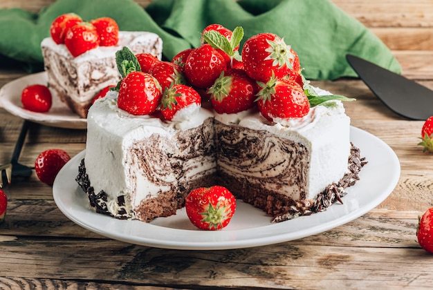 Torta di mousse di zebra al cioccolato con fragole su sfondo rustico in legno