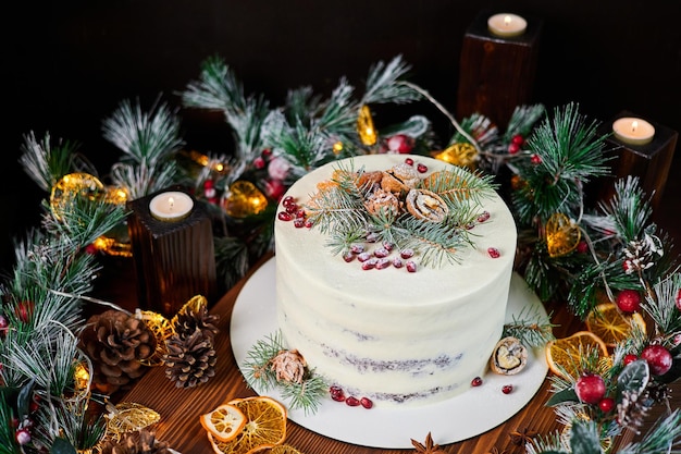 Torta di Natale con crema decorata con rami di abete, noci e semi di melograno