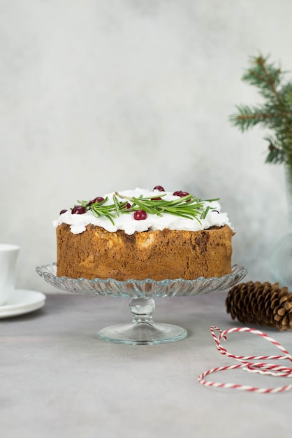 Torta di Natale con rosmarino e bacche rosse su un supporto su sfondo grigio