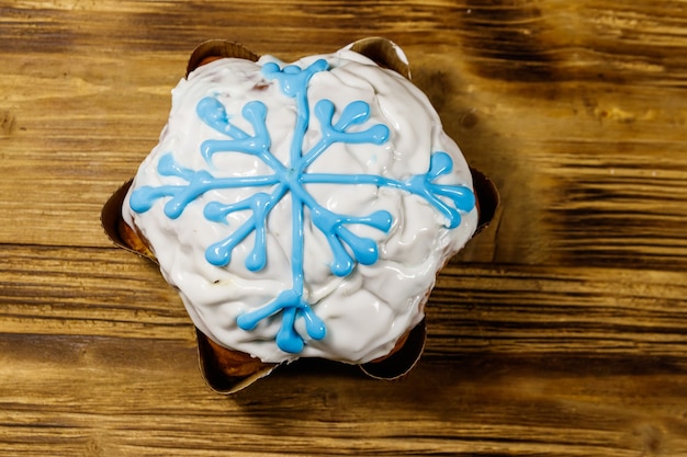 Torta di Natale decorata con glassa bianca e fiocco di neve sul tavolo di legno. Vista dall'alto