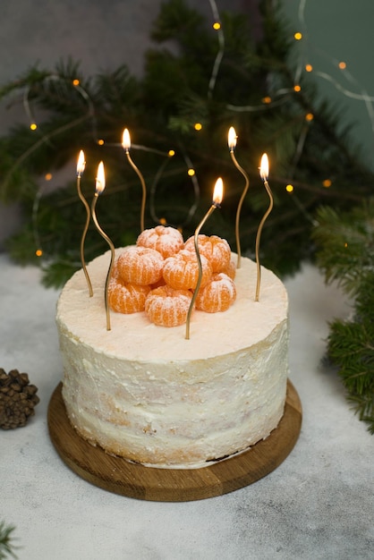 Torta di Natale fatta in casa con rami di abete candele su sfondo grigio