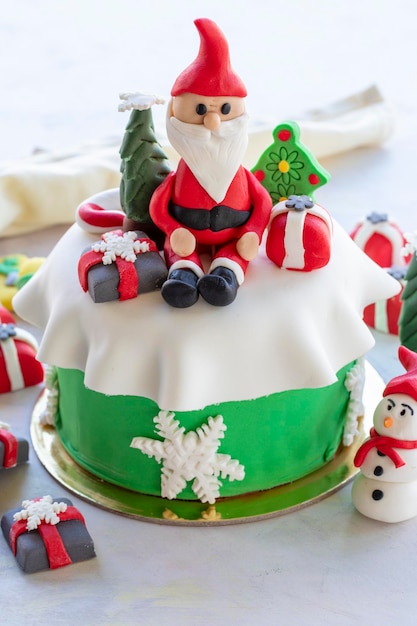 Torta di Natale preparata con pasta di zucchero Con albero di Natale di Babbo Natale e figure regalo su di esso