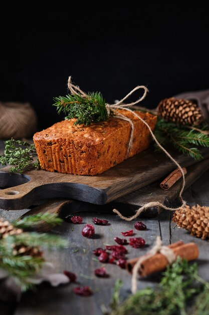 Torta di panpepato di Capodanno con kumquat, bacche essiccate e frutta. Un dolce festivo decorato con ramoscelli di abete rosso e bacche e frutti freschi.