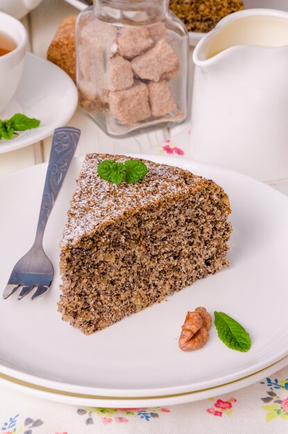 Torta di papavero con noci e crema pasticcera alla vaniglia su un fondo di legno bianco.