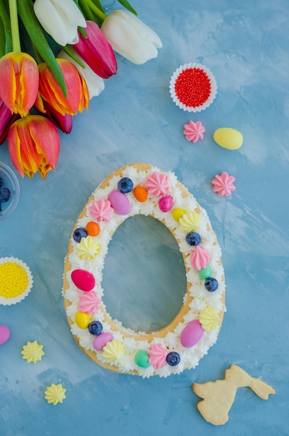 Torta di Pasqua a forma di uovo con crema di caramelle uova biscotti meringa e spruzza sulla parte superiore della carta di Pasqua