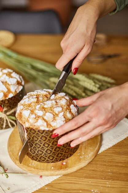 Torta di Pasqua del taglio della mano della donna sulla tavola rustica di legno