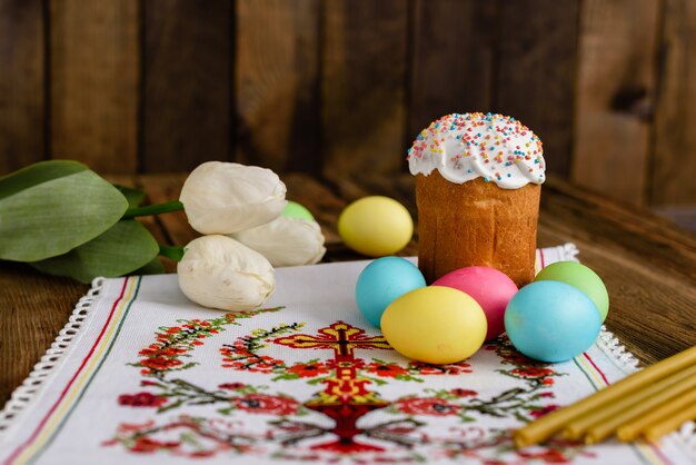 Torta di Pasqua e uova colorate su un tavolo di legno.