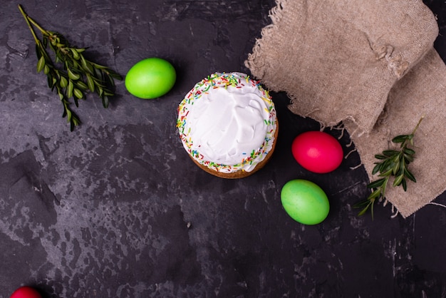 Torta di Pasqua e uova colorate su uno sfondo scuro