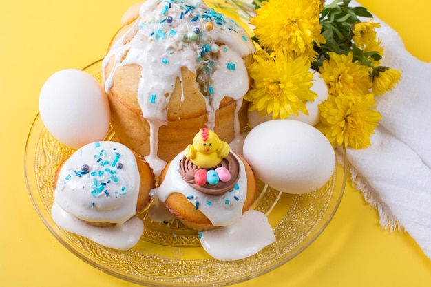 Torta di Pasqua e uova con fiori su sfondo giallo Il concetto della festa di Pasqua