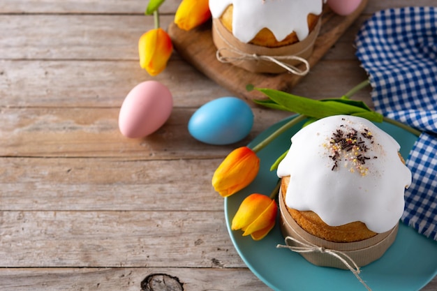 Torta di Pasqua tradizionale, uova colorate e tulipani su tavola di legno