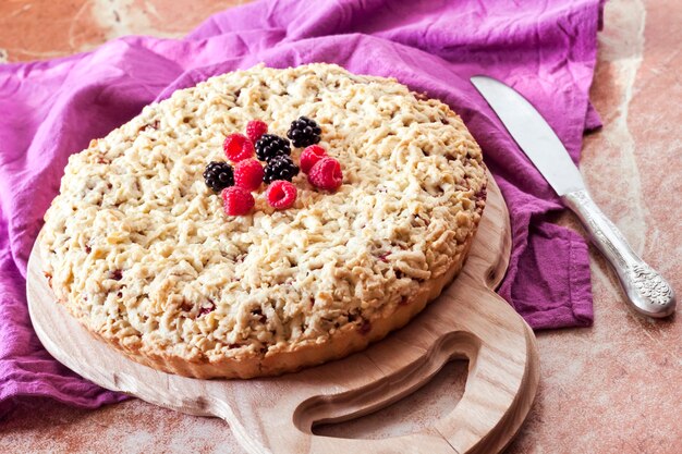 Torta di pasta frolla ai frutti di bosco fatta in casa con crumble su tavola di legno e panno viola