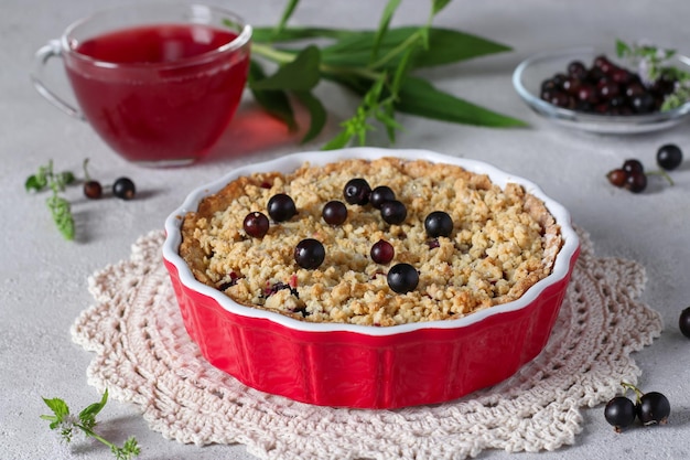 Torta di pasta frolla fatta in casa con ribes nero in forma di ceramica su sfondo grigio chiaro