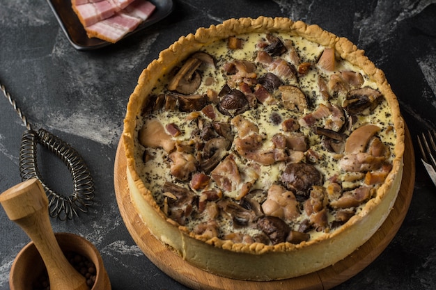 Torta di quiche ai funghi con champignon e formaggio su sfondo scuro