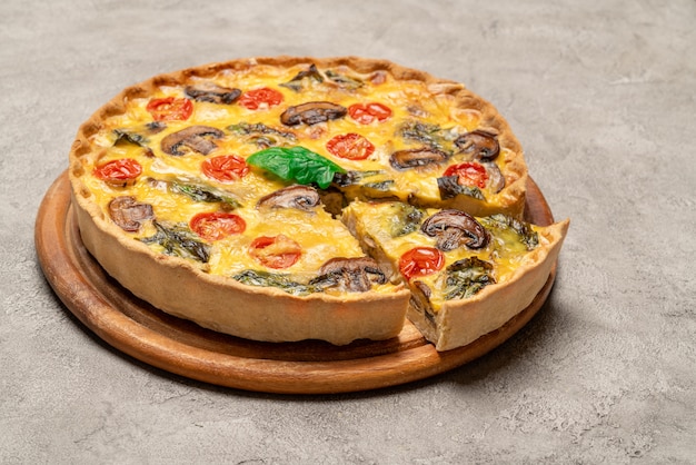 Torta di quiche casalinga al forno francese tradizionale sul tagliere di legno