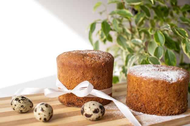 Torta di spugna con zucchero in polvere sul tavolo con uova di quaglia Una pianta verde Luogo per il testo