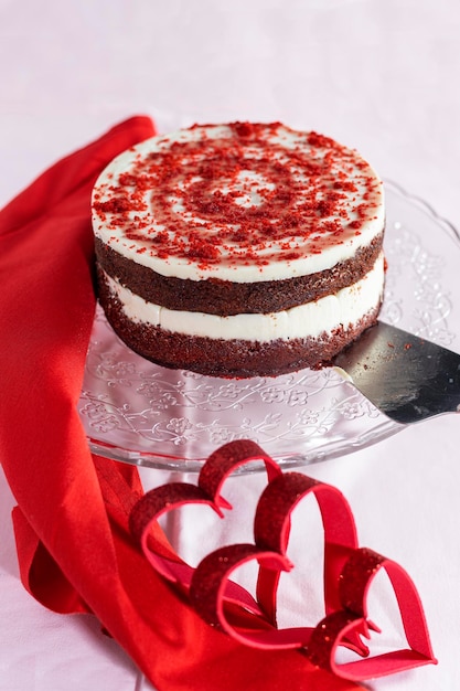 torta di velluto rosso con cuori rossi e tovagliolo su sfondo chiaro