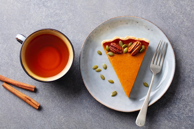 Torta di zucca su un piatto con una tazza di tè Sfondo grigio Primo piano Vista dall'alto