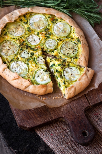 Torta di zucchine fatta in casa e formaggio di capra su una tavola di legno rustica scura