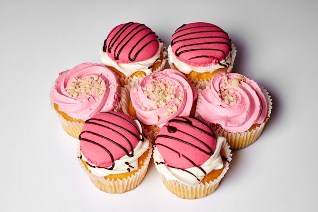 Torta dolce, deliziosi muffin con crema rosa. Dolce delizia. Set di torte su una parete bianca