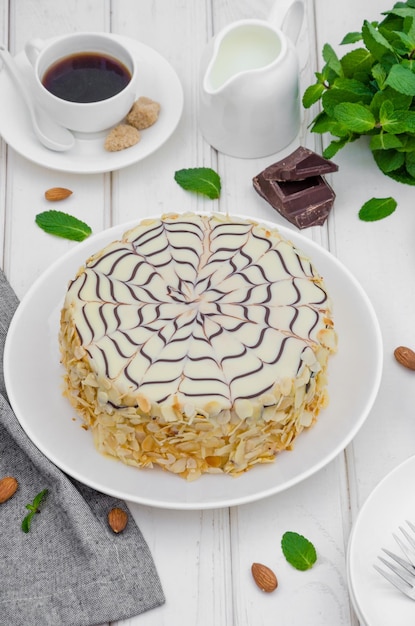 Torta Esterhazy ungherese tradizionale su un piatto bianco con una tazza di caffè, menta e mandorle