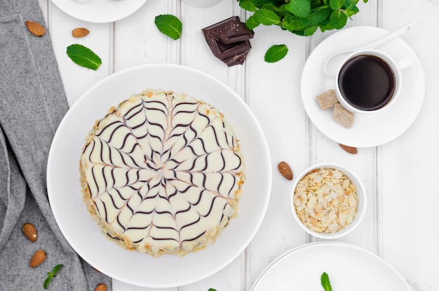 Torta Esterhazy ungherese tradizionale su un piatto bianco con una tazza di caffè, menta e mandorle