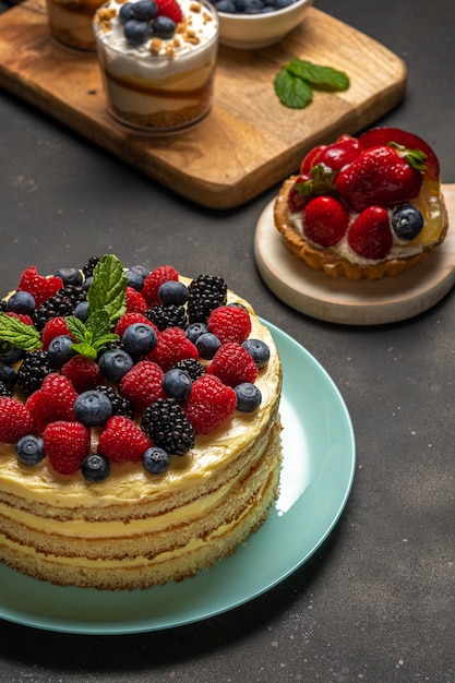 Torta fatta in casa con frutti di bosco freschi e dolci su sfondo scuro.