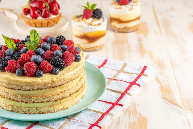 Torta fatta in casa con frutti di bosco freschi su fondo di legno.