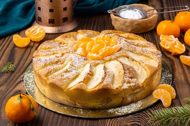 Torta fatta in casa con mandarini e mandarini su tavola in legno rustico