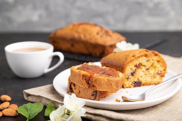 Torta fatta in casa con uvetta mandorle caramello morbido e una tazza di caffè su uno sfondo di cemento nero Vista laterale fuoco selettivo