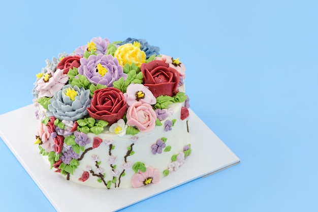 Torta fatta in casa decorata con bellissimi fiori su sfondo blu, concetto di torta minimale